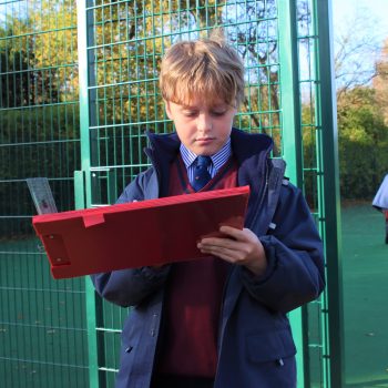 school boy outside looking at his clipboard