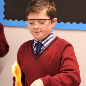 young boy wearing safety goggles and using a bunsen burner