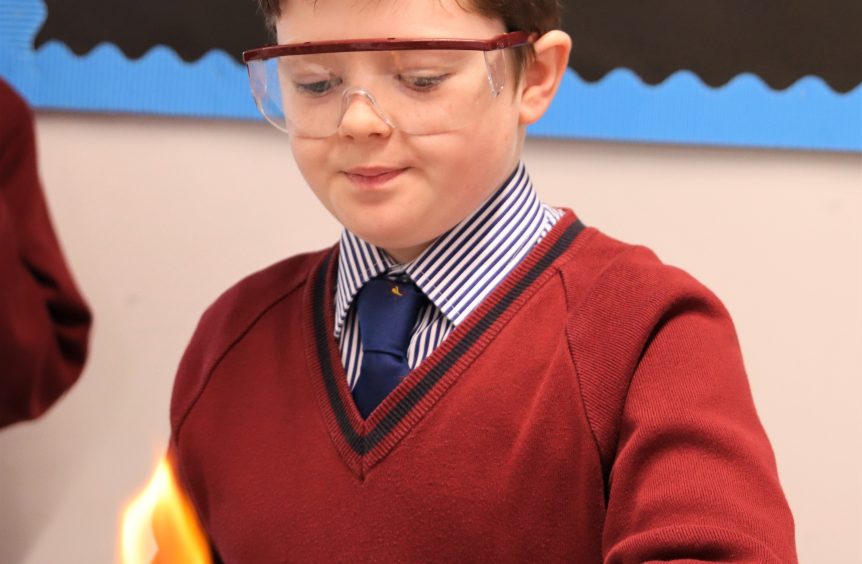 young boy wearing safety goggles and using a bunsen burner