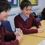 two school boys in uniform playing cards
