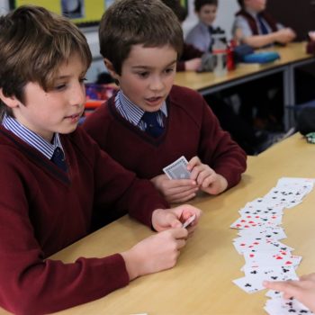 two school boys in uniform playing cards