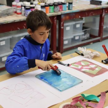 a child painting with a roller at a boys school in Chesham