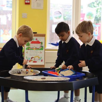 Boys playing with sand around a table