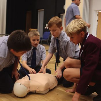 4 boys surround a CPR doll