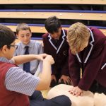 4 school boys practicing how to perform CPR