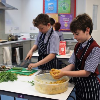 students chopping up vegetables and rolling up dough/mix