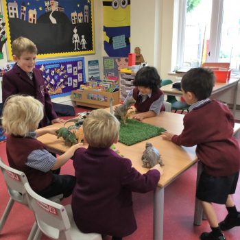 A group of boys playing with dinosaurs in the classroom
