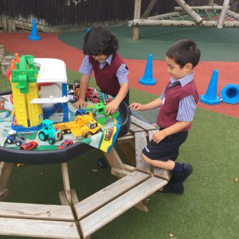 Boys playing with toys outside on a garden bench