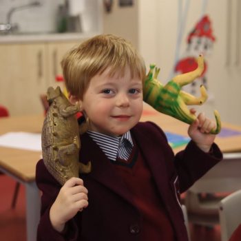 A boy holding dinosaurs to play with