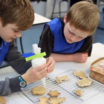 Students adding icing to biscuits