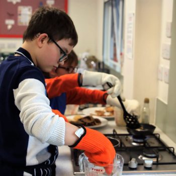 Student adding something into a glass jug wearing safety gloves