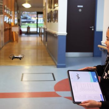 Student holding an iPad to control a drone