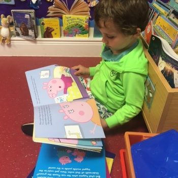 young child reading Peppa Pig