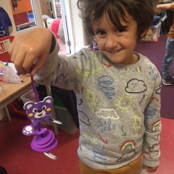 child holding a purple teddy toy with string