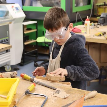 1 student wearing goggles at the woodmaking station