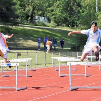 2 students jumping over hurdles